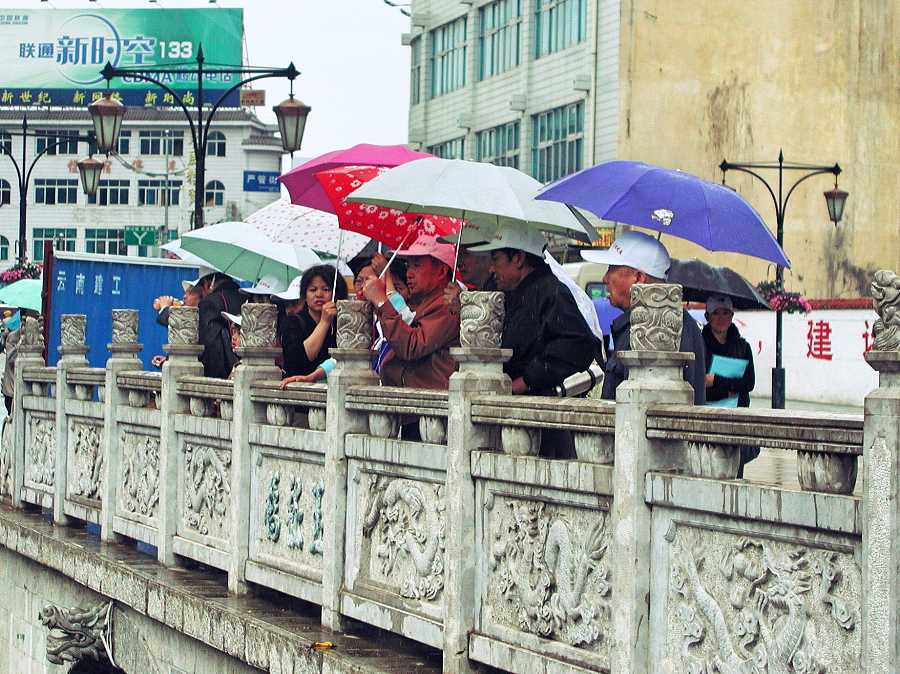 People with umbrellas standing in the rain. Li Jiang, China