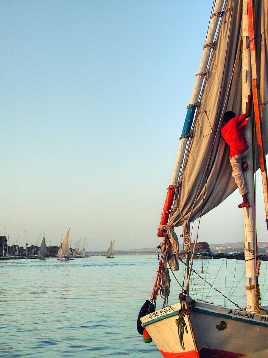 Sailor climbs the mast of a felucca on the Nile in Aswan