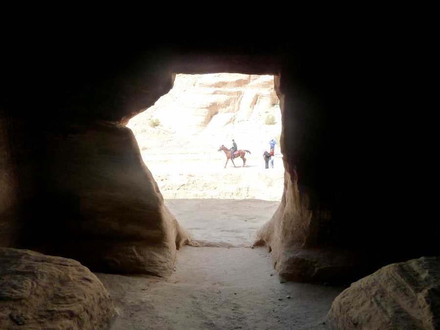 Horse rider goes past a cave entrance