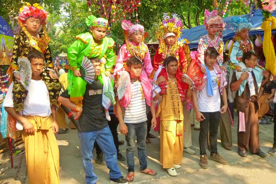Shan boys are carried on the shoulders of members of their families