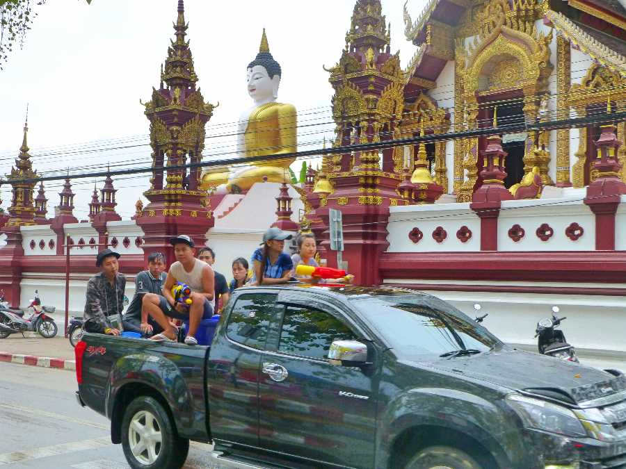 Songkran revellers drive past a Temple