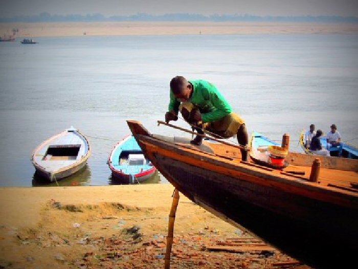 Working on a wooden boat, using hand-made tools, beside the Ganges River, Varanasi, India.